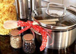 A pot, a wooden spoon, and some spices on a table.