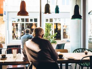 Packing guide for seniors- a senior sitting in a coffee house