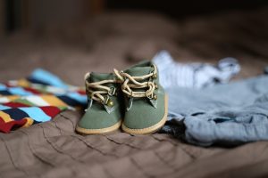 A pair of baby shoes and some clothes in the background.