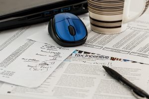 Paperwork on a table with a computer mouse and a pen.