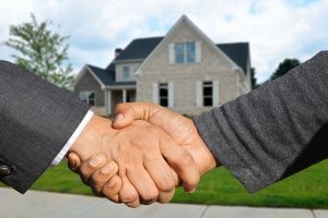 Shaking hands in front of a home