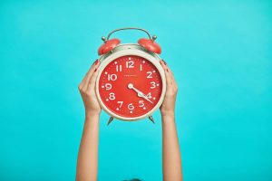 person holding a red clock