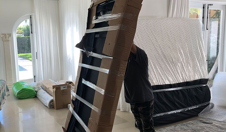 Mover holding packed piece of furniture upright.