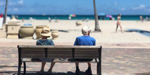A picture of two people sitting on a bench on the beach