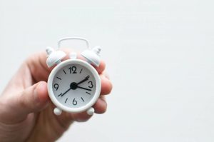 A person holding a small white clock