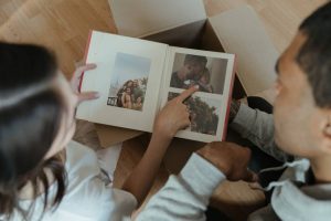 Woman and man are watching the photographs in the album and talking about them.