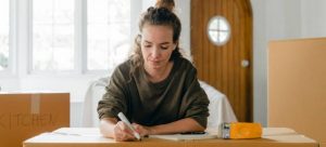 A millennial girl taking notes on long distance moving advice on boxes