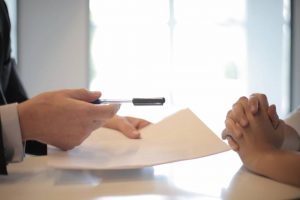 A person gettign insurance papers and a pen