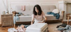 A girl packing her suitcase on the floor in a messy room