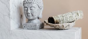 a small Buddha statue and sage next to it