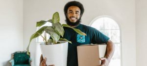 Mover holding a box and a plant.