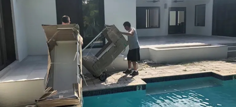 people carrying furniture by the pool