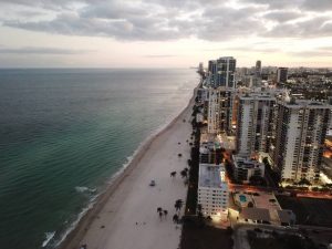 A person thinking of spending the summer in Hallandale Beach while looking at the buildings of this city.