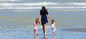 mom on the beach with twin girls following moving trends in Florida