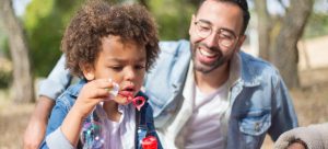 a kid blowing bubbles with dad