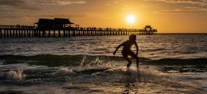 Surfer at Naples Pier during sunset