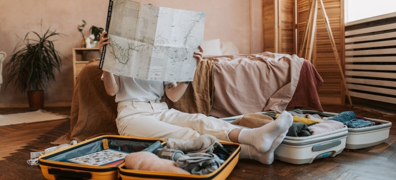 a woman reading a map while sitting in a pile of clothes