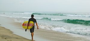 a surfer on a beach in Boca Raton thinking about Fort Lauderdale vs Boca Raton