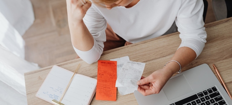 a woman looking at receipts on her work desk in order to calculate the moving costs
