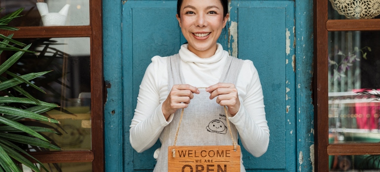 woman holding an open sign after finding some of the best places in Florida to start a small business