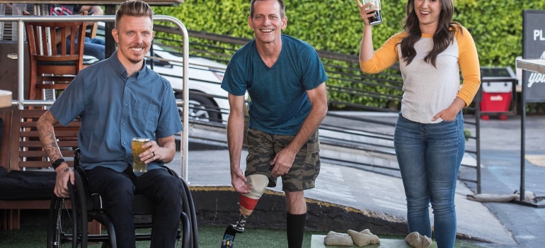 two men with disabilities and a woman playing sports after moving to Miami with a disability