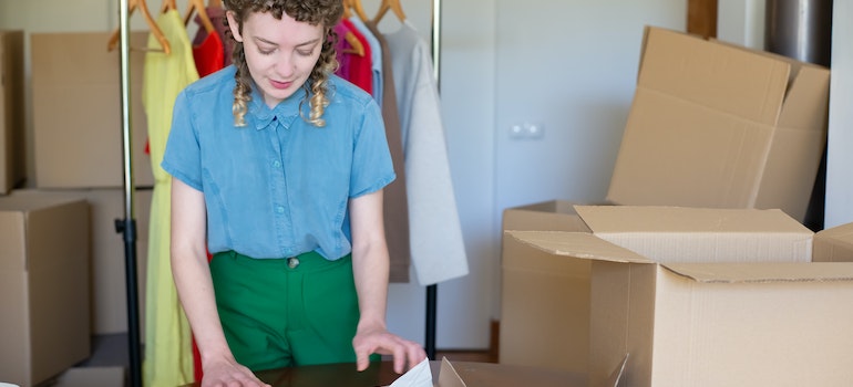 Woman wrapping clothes while reading guide to moving to Miami on a budget long the way
