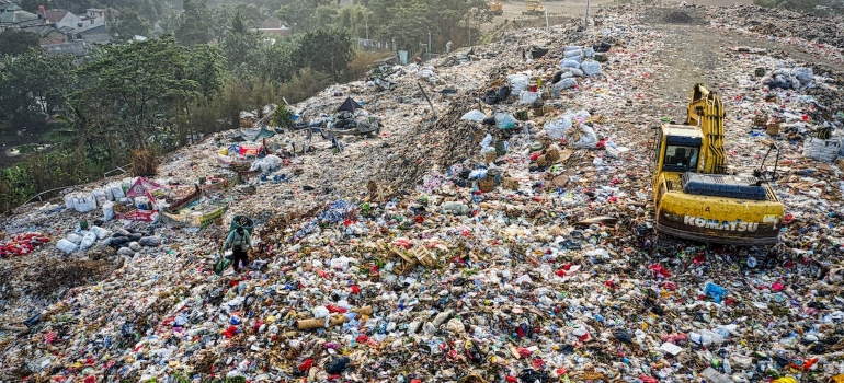a landfill full of garbage with an excavator working on it