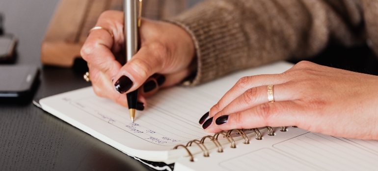 Person writing a list of things they need to do before moving from California to Miami