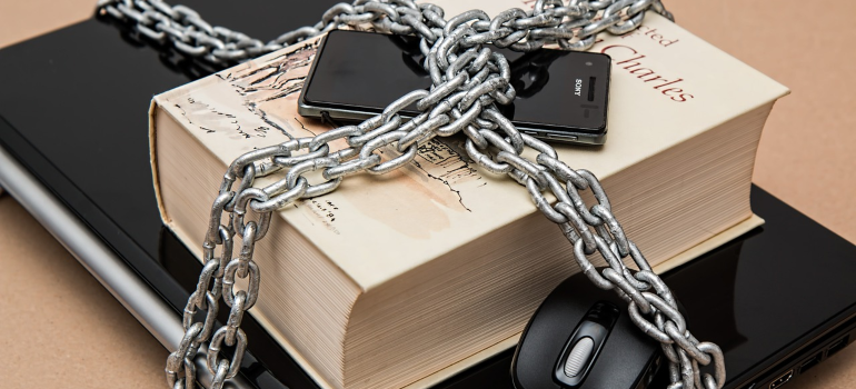 a laptop, book and a phone secured with a chain