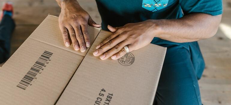 A person closing a moving box