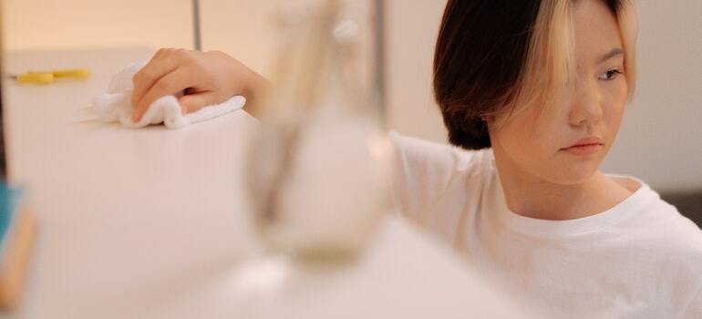 A person following the ultimate move out cleaning checklist and cleaning shelves