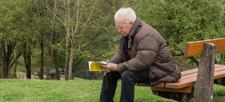 a retiree sitting on a bench, reading a book and thinking about the pros and cons of retiring in Miami