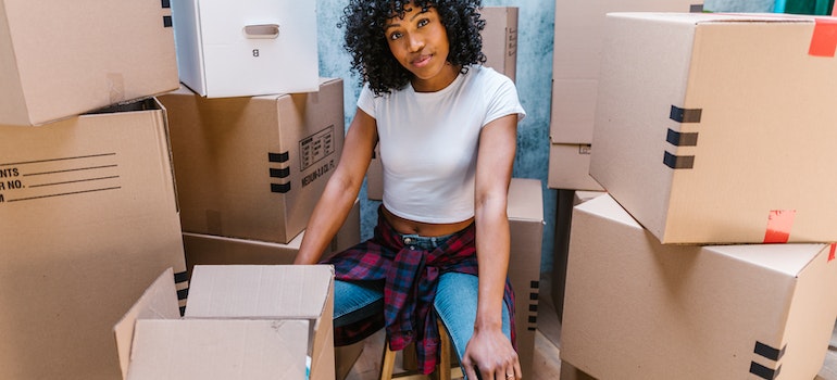 Woman sitting surrounded by boxes trying to prevent damaging your belongings during a relocation