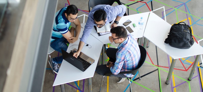 3 men looking at the laptop in co-working space