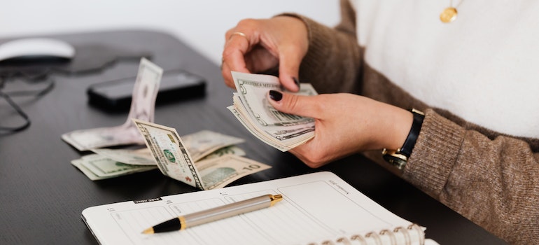 person counting money before deciding between buying vs renting a home in Miami in 2023