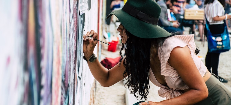 A female artist painting the wall after moving to Miami as an artist.