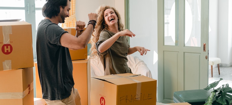 A man and a woman laughing while unpacking.