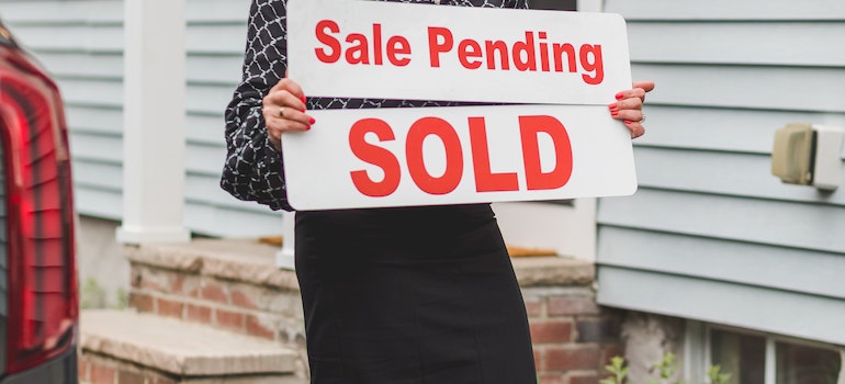 holding a sold home sign after following the latest Fort Lauderdale real estate trends